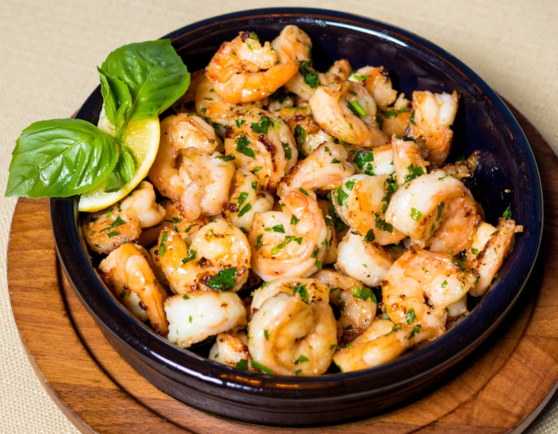 Garlic butter shrimp in a skillet with parsley and lemon wedges